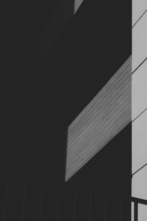Free A minimalist black and white photo highlighting geometric shadows on building surfaces. Stock Photo