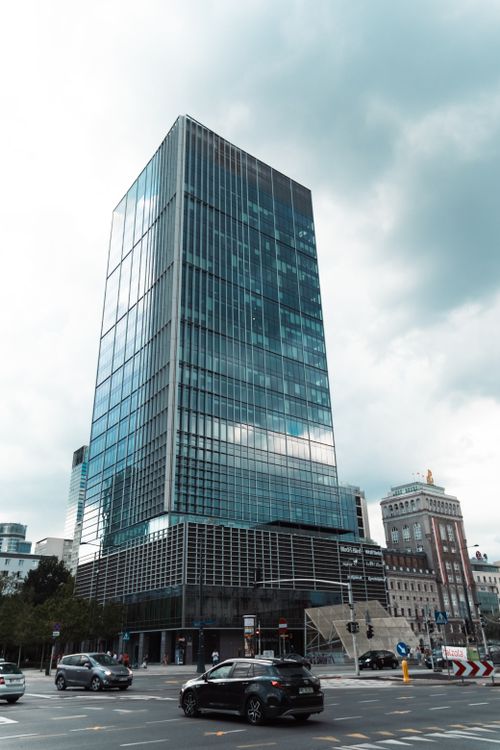 Free Modern glass skyscraper in city center with street view under cloudy sky. Stock Photo