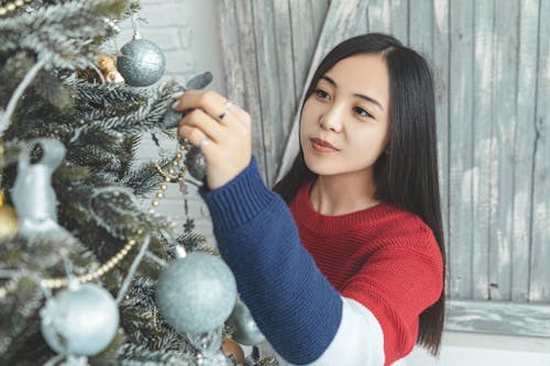 Charming Asian woman decorating Christmas tree