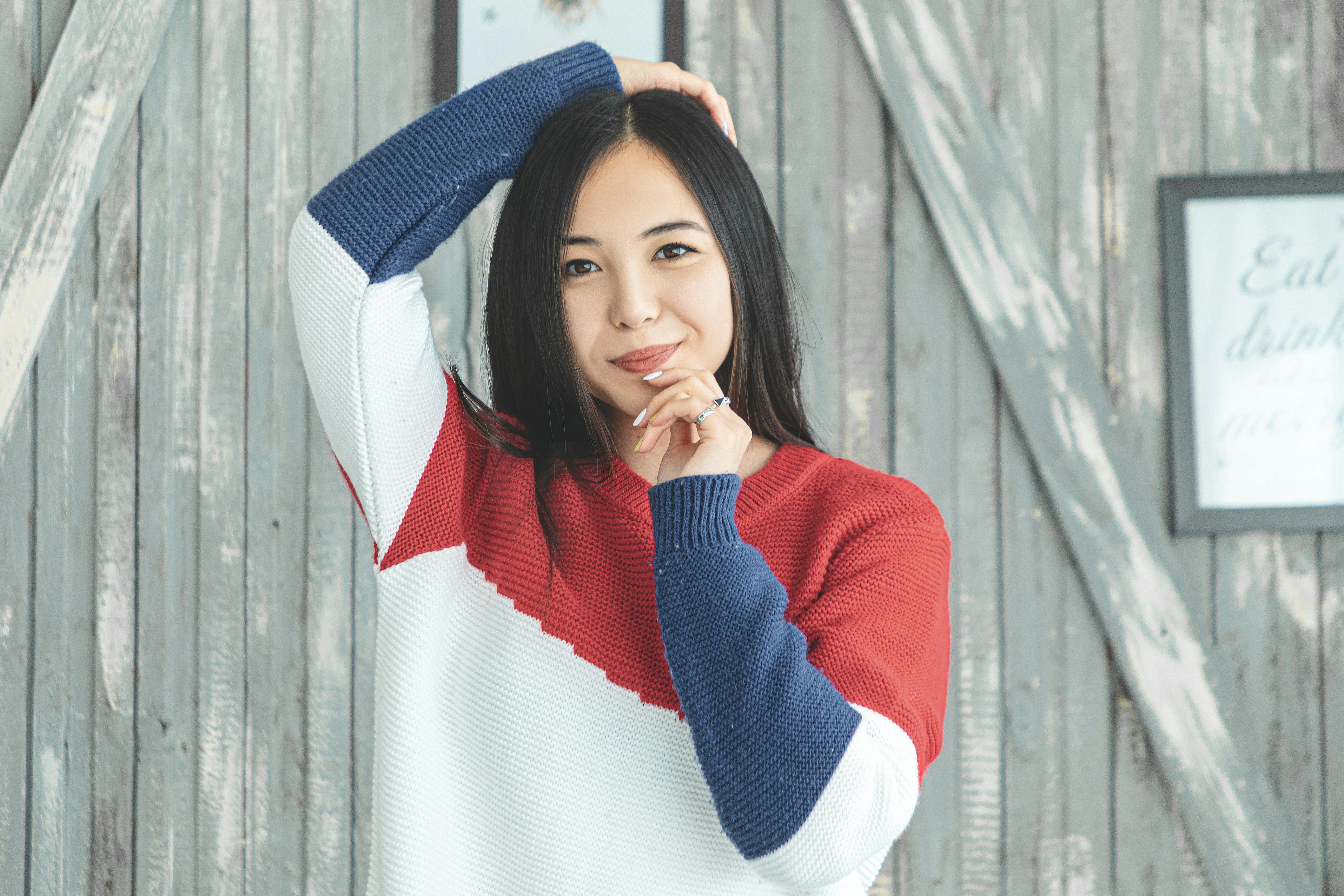 一个女人穿着彩色针织毛衣，在木制背景下摆姿势