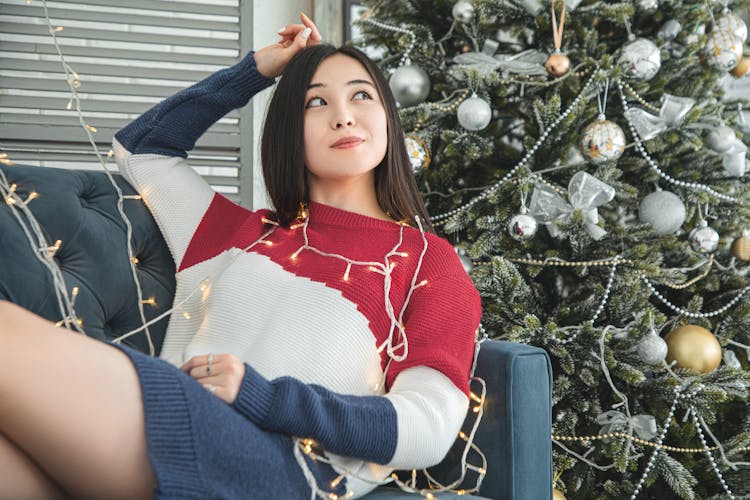 Woman With String Lights Near Christmas Tree