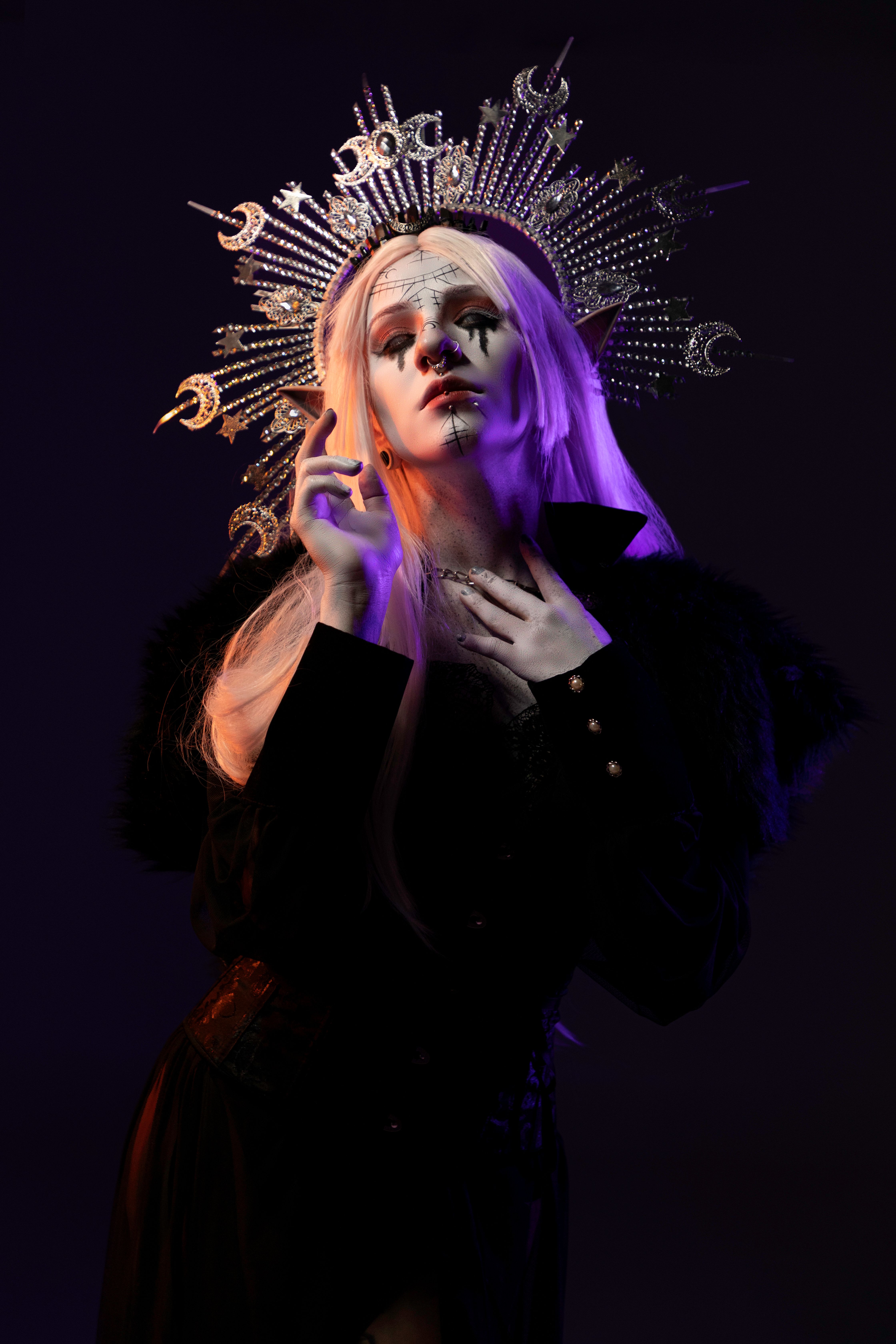 Elegant portrait of a person wearing ornate spiked crown in dramatic lighting.