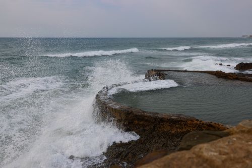 Free Dynamic waves crash against a natural rock pool on a cloudy day at the seaside. Stock Photo