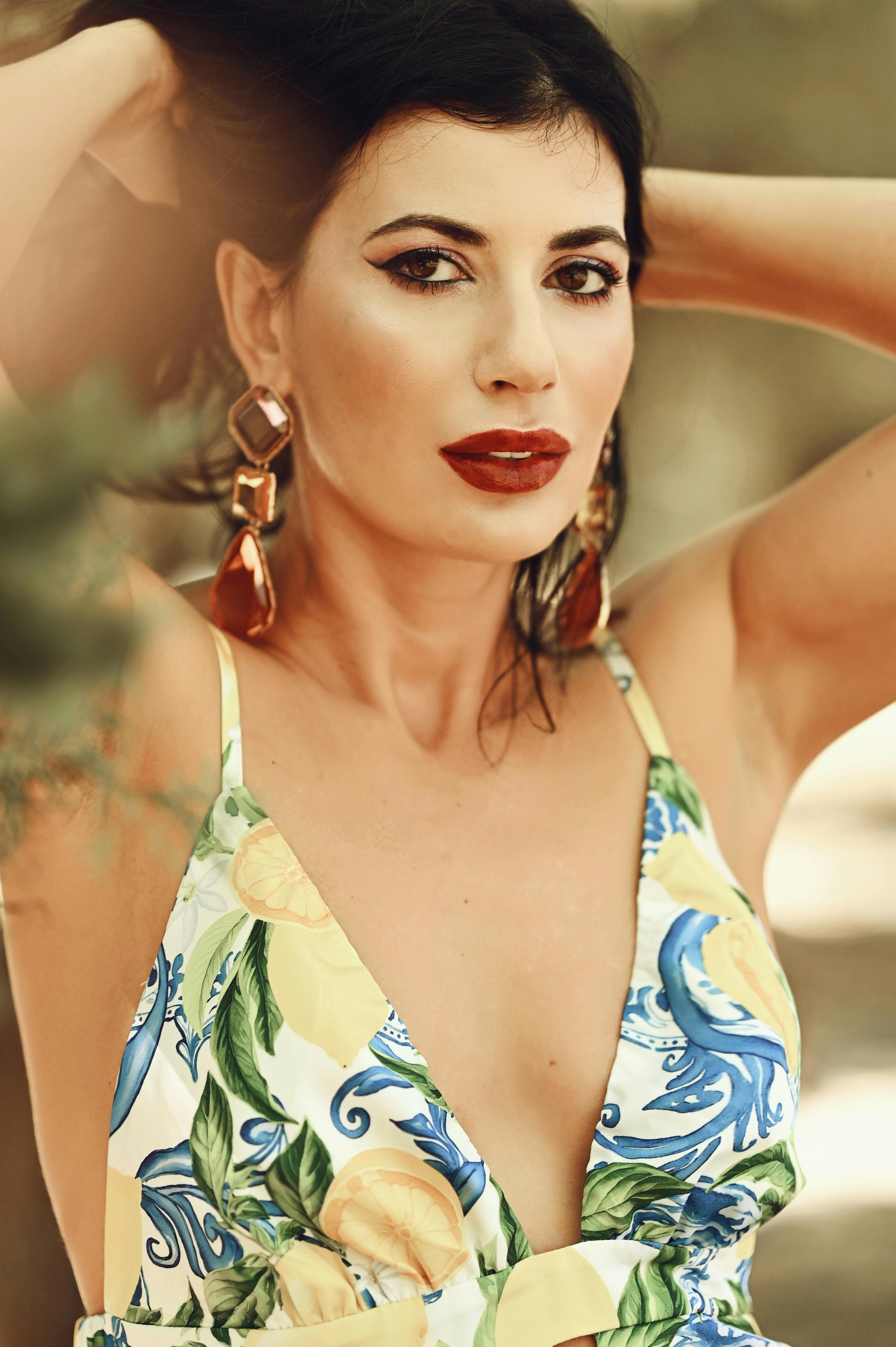 Stylish woman in colorful floral dress posing confidently outdoors.