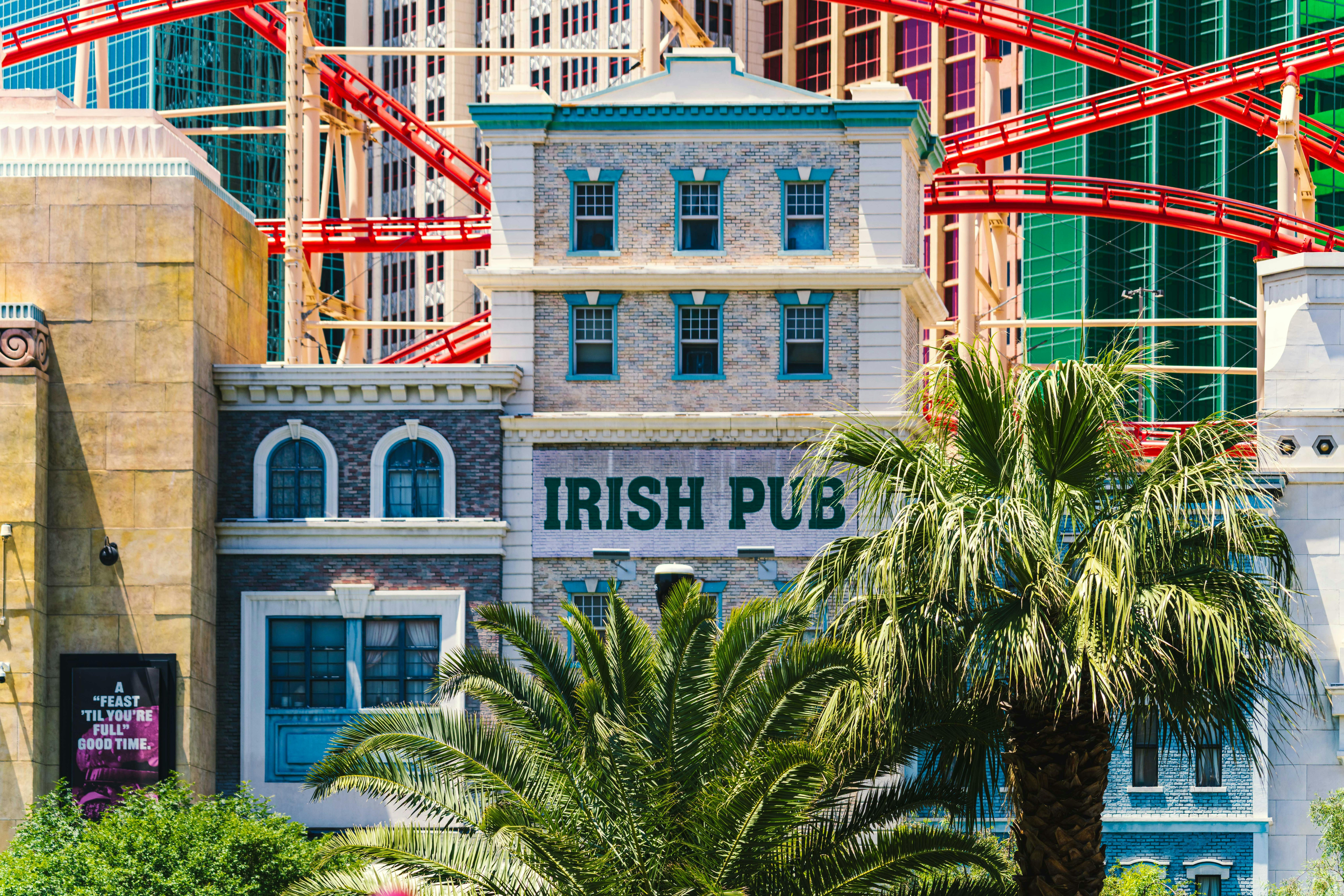 Colorful Irish pub facade with palm trees and roller coaster on the Las Vegas Strip.