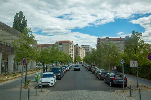 Free A sunny view of a European residential street lined with parked cars and trees. Stock Photo
