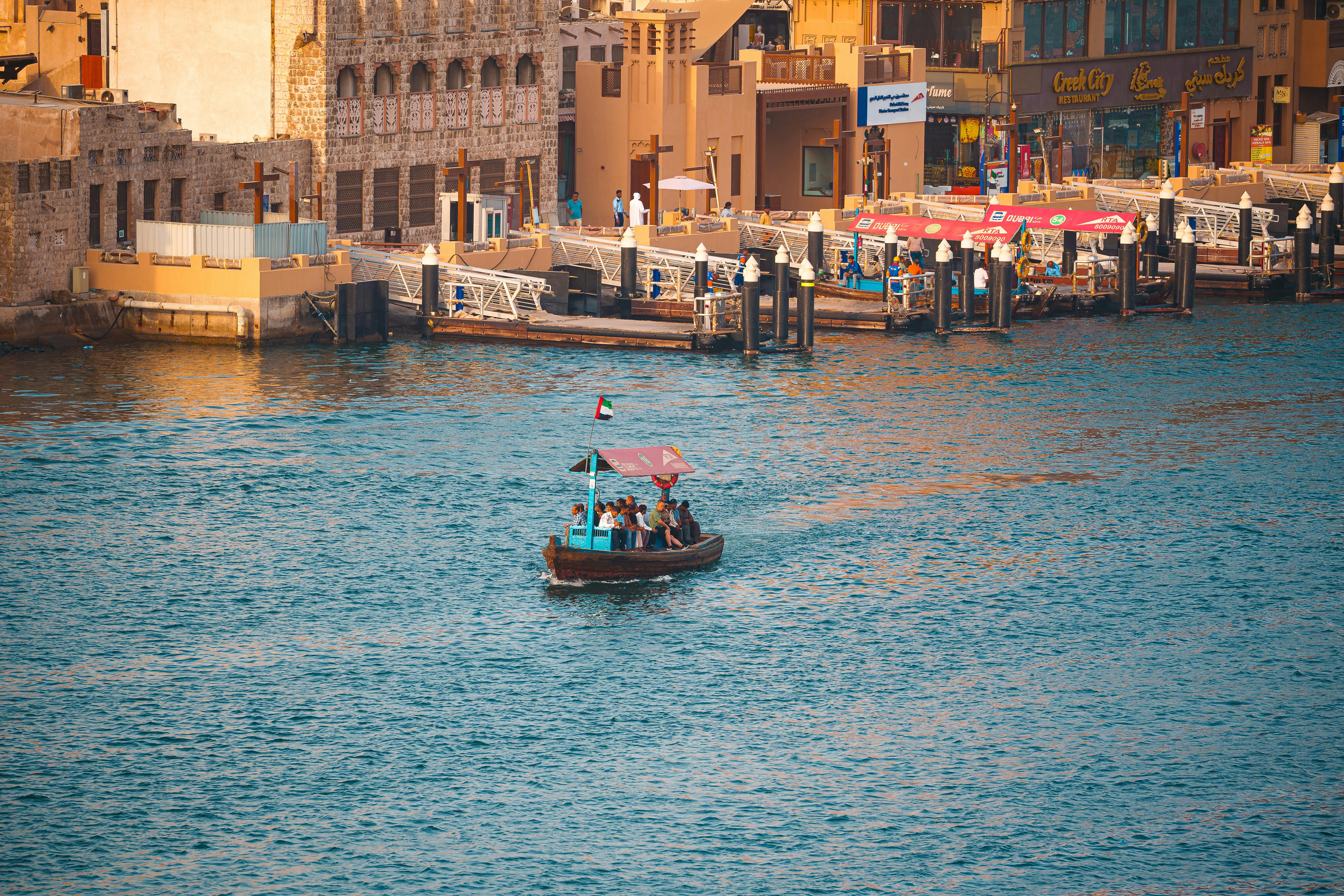Capture of a traditional abra boat on Dubai Canal with scenic views at sunset, showcasing Dubai's ri