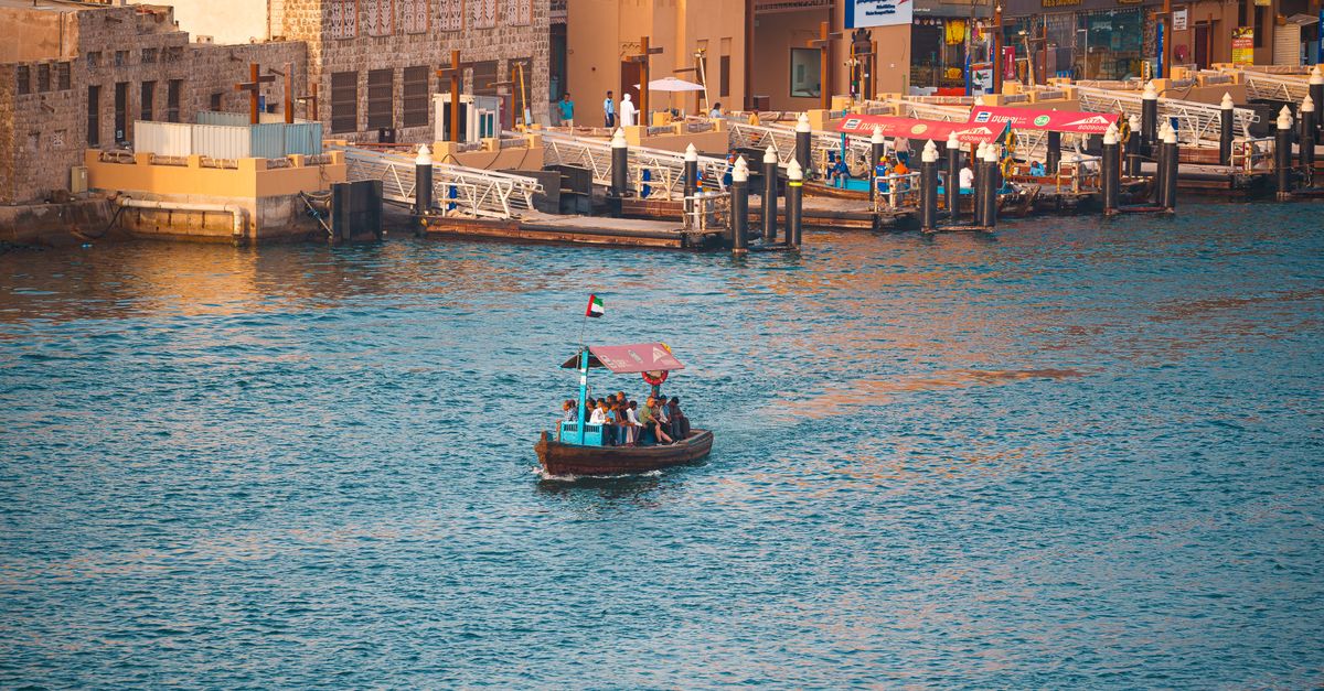 Capture of a traditional abra boat on Dubai Canal with scenic views at sunset, showcasing Dubai's ri