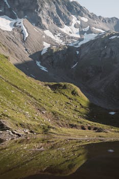 Stunning alpine landscape featuring a tranquil lake with mountain reflections and pristine snow-capped peaks.