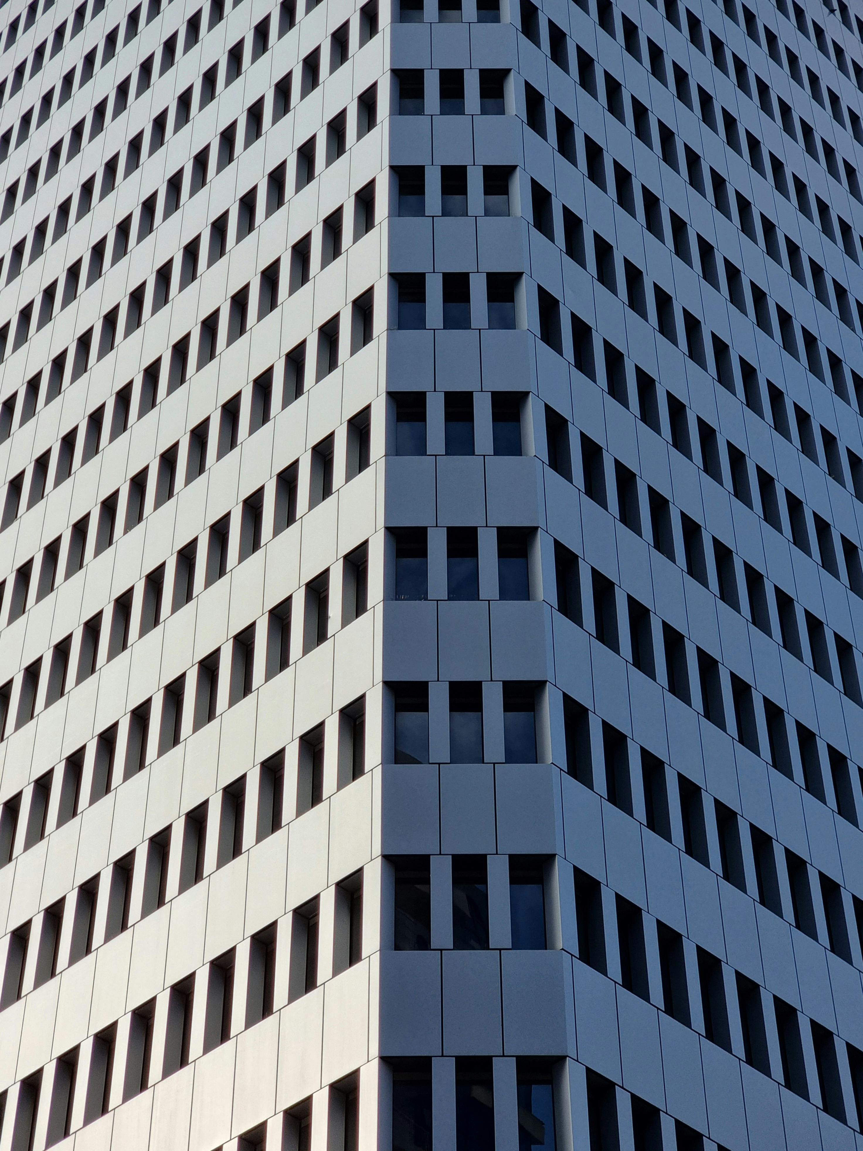 Free Symmetrical corner view of a modern high-rise building facade with geometric patterns. Stock Photo
