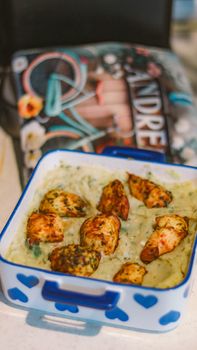Delicious oven-baked chicken served on a creamy spinach dip in a heart-designed dish.