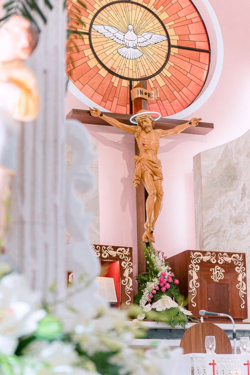 Free Elegant church interior featuring a detailed crucifix and vibrant stained glass window. Stock Photo