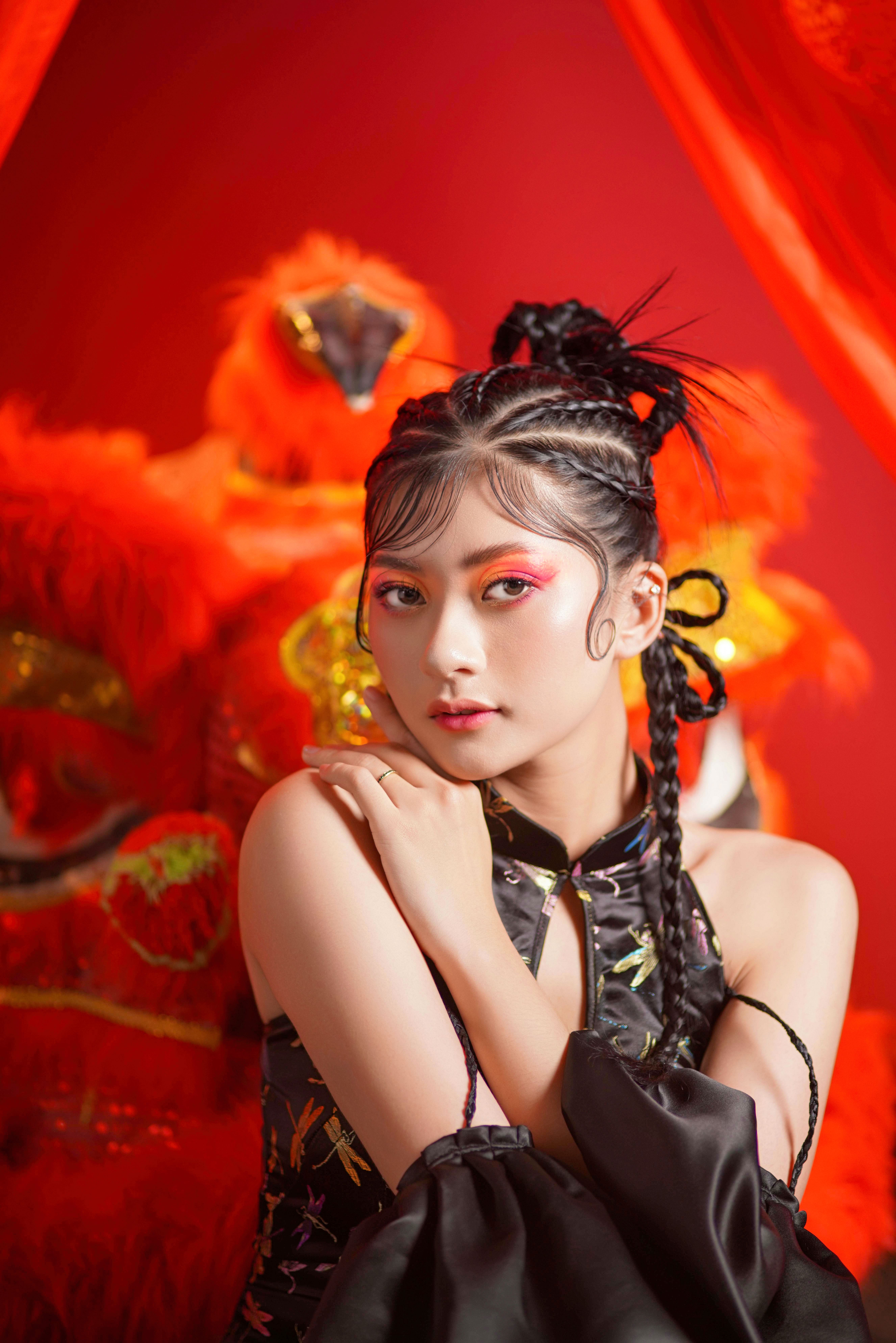 Stunning portrait of a woman in traditional Asian dress with a vibrant red backdrop, embodying cultural elegance.