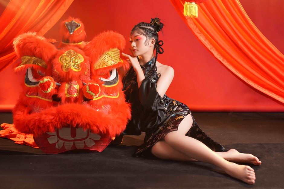 Young woman in elegant attire with vibrant lion dance costume, embracing cultural heritage.