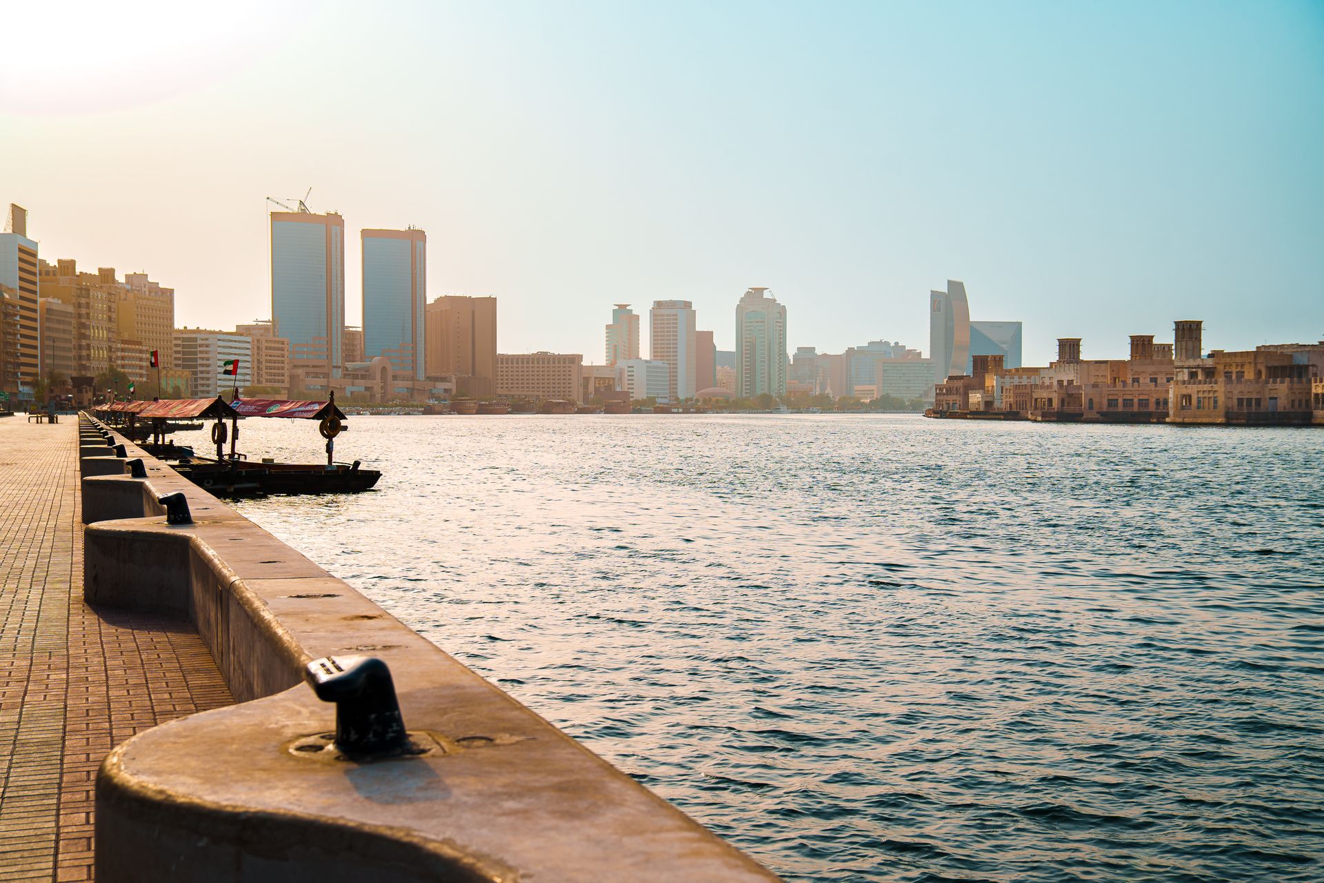 View of Dubai Creek with skyline and promenade in daylight, showcasing modern Dubai architecture.