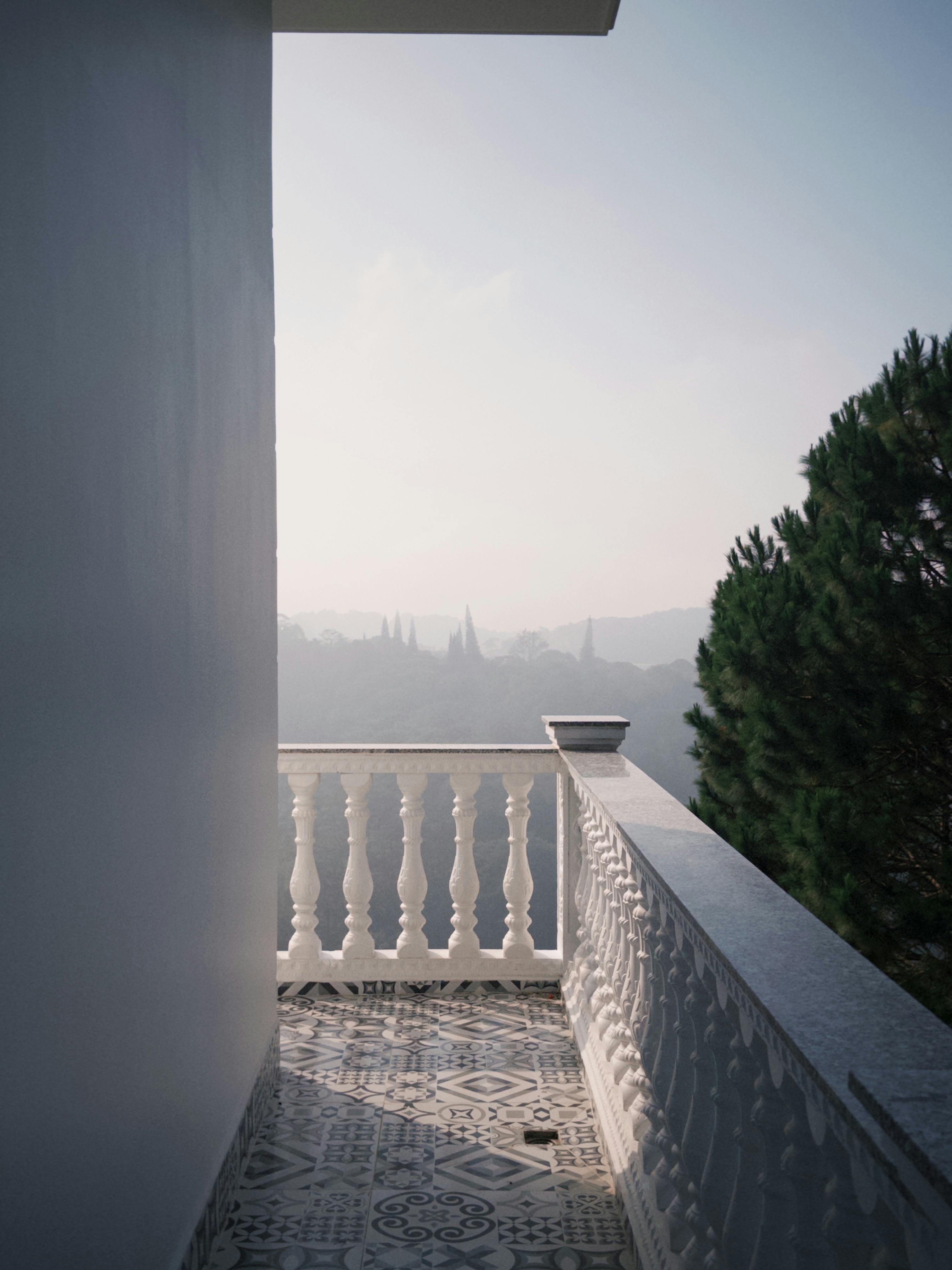 Elegant balcony overlooking a misty landscape with trees in the distance.