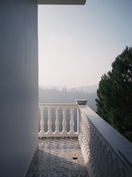 Elegant balcony overlooking a misty landscape with trees in the distance.