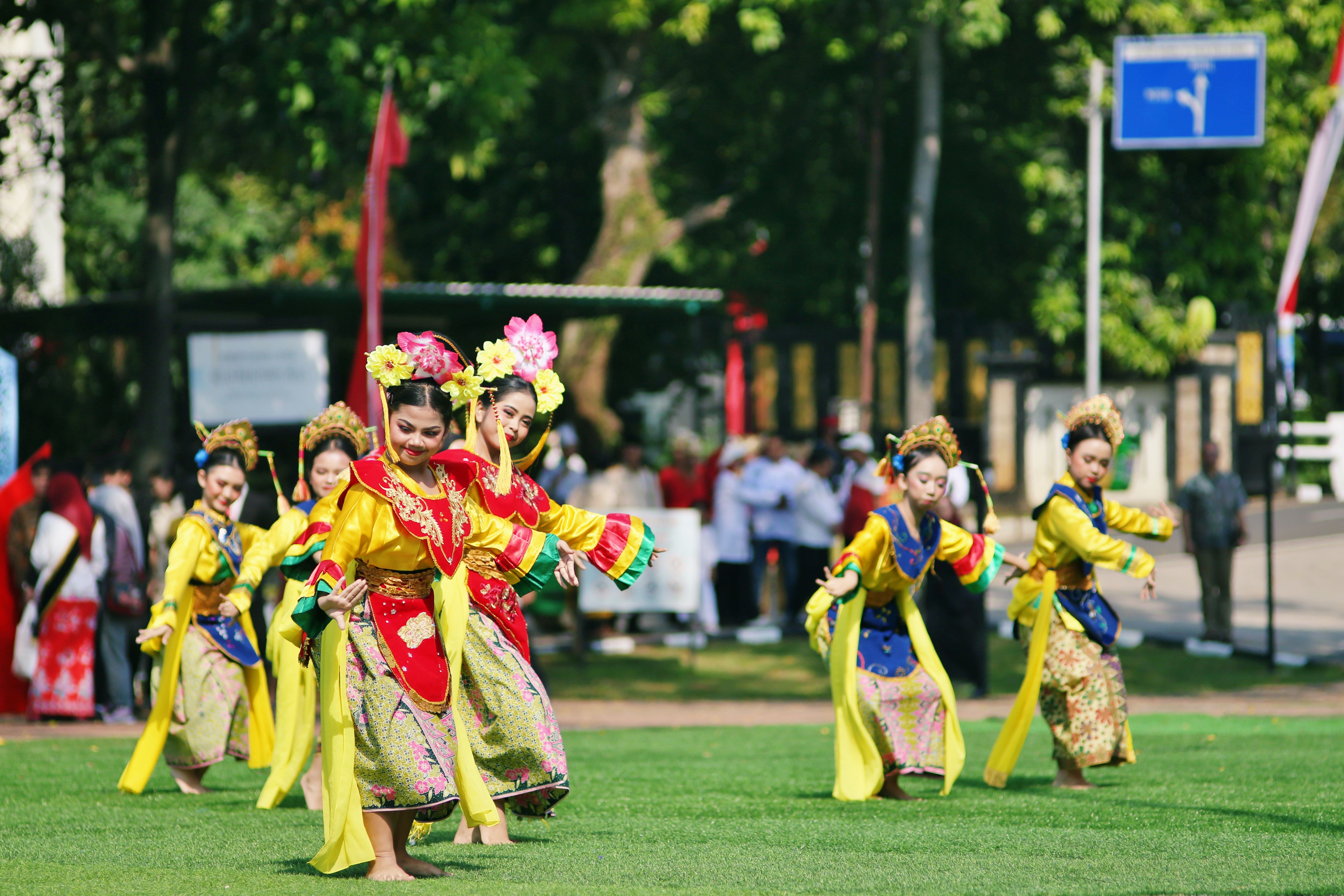 Group of women in traditional Asian costumes performing an outdoor cultural dance with vibrant colors.