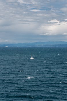 A single sailboat navigates the vast waters of the Adriatic Sea near Piran, Slovenia.