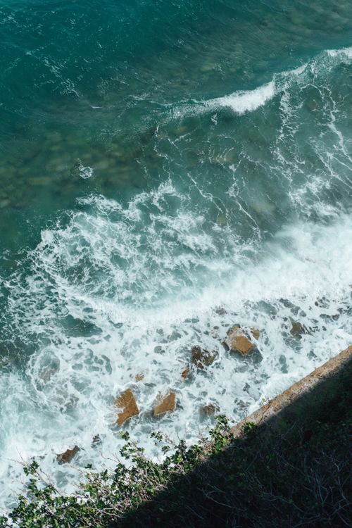 Free Aerial view of waves crashing against a rocky shoreline in Piran, Slovenia, showcasing vibrant teal waters. Stock Photo