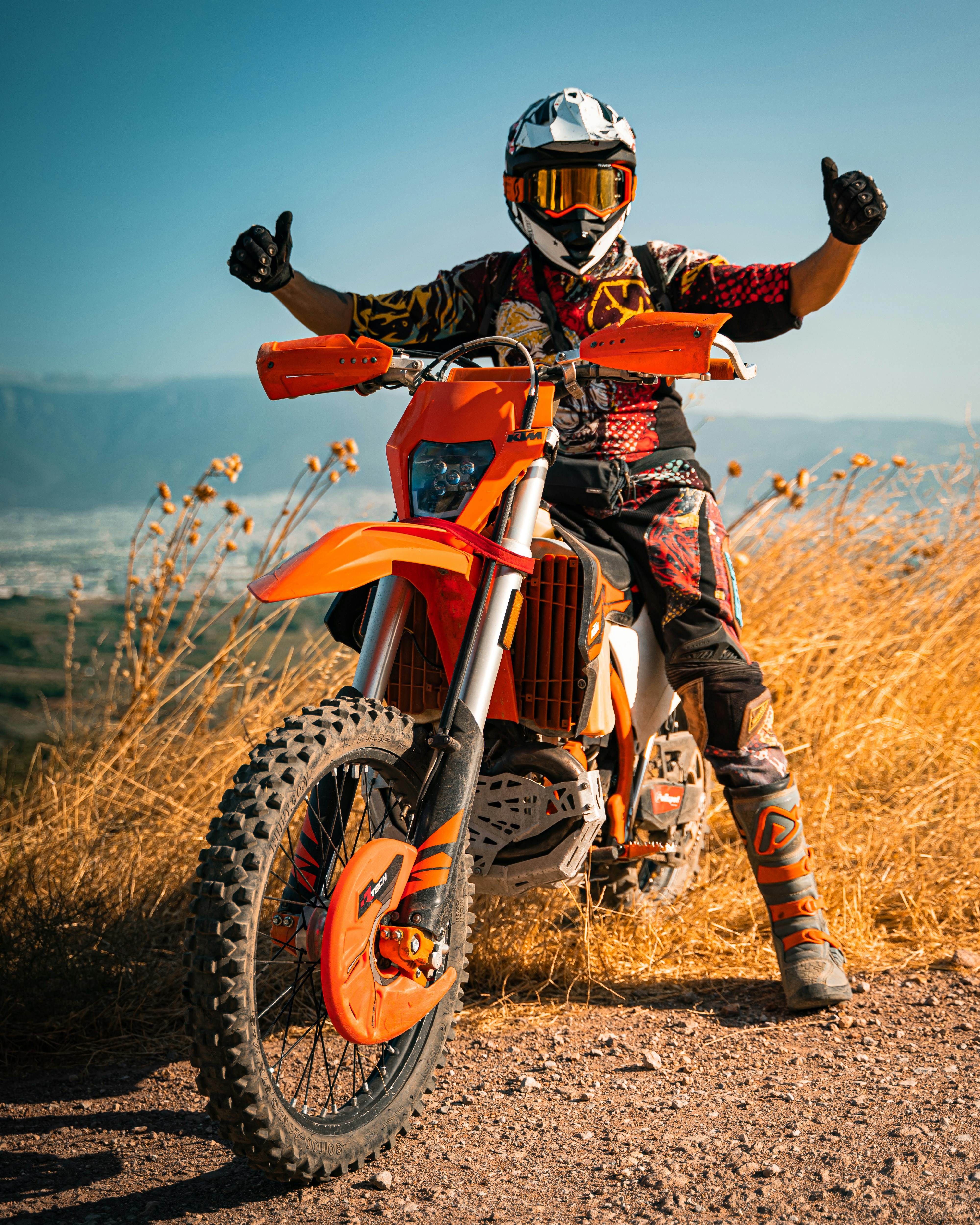 A motocross rider poses with a dirt bike under a clear blue sky in Gündoğdu, Türkiye.