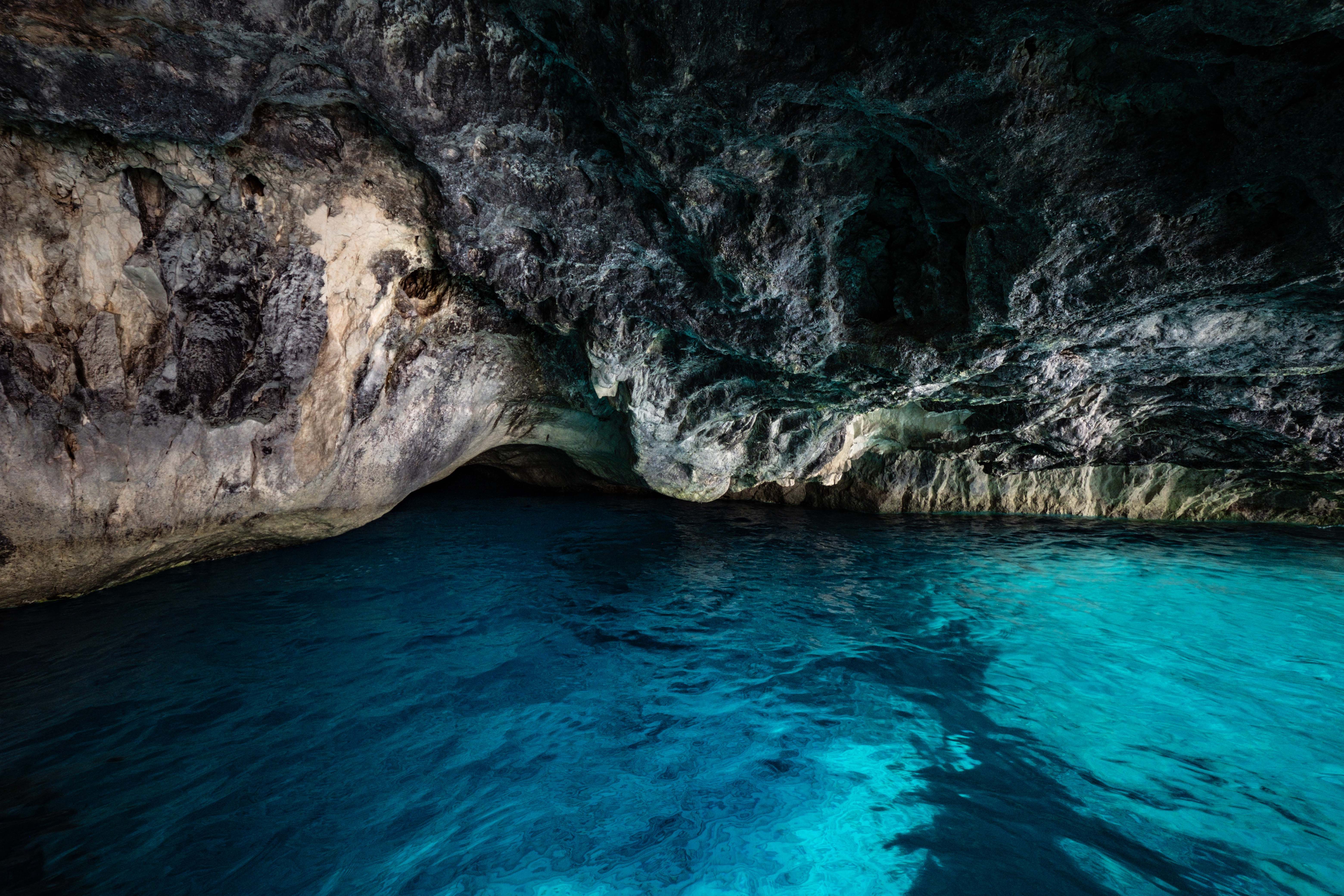 Discover the breathtaking beauty of an underground cave with clear blue waters and rugged rock formations.