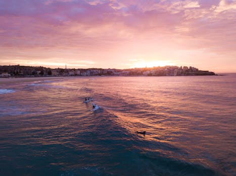 日落时分，邦迪海滩上空，冲浪者骑乘海浪的鸟瞰图