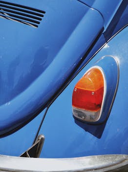 Detailed view of a classic blue car's tail light and body, showcasing vintage automotive design.