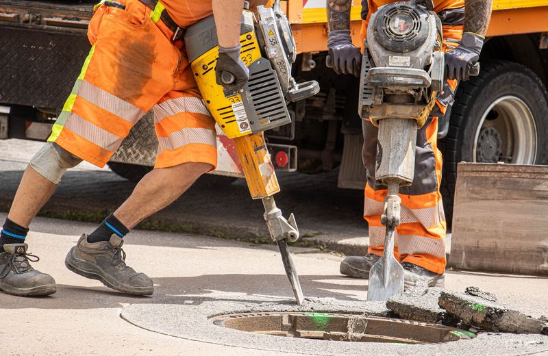 Workers repairing damaged asphalt pavement