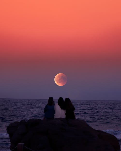 Trois Femmes Assises Sur Un Rocher En Face De L'océan