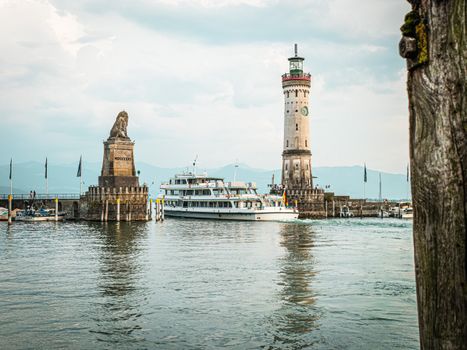 Lindau Lighthouse with Bavarian Lion statue and ferry in Lake Constance, Germany.