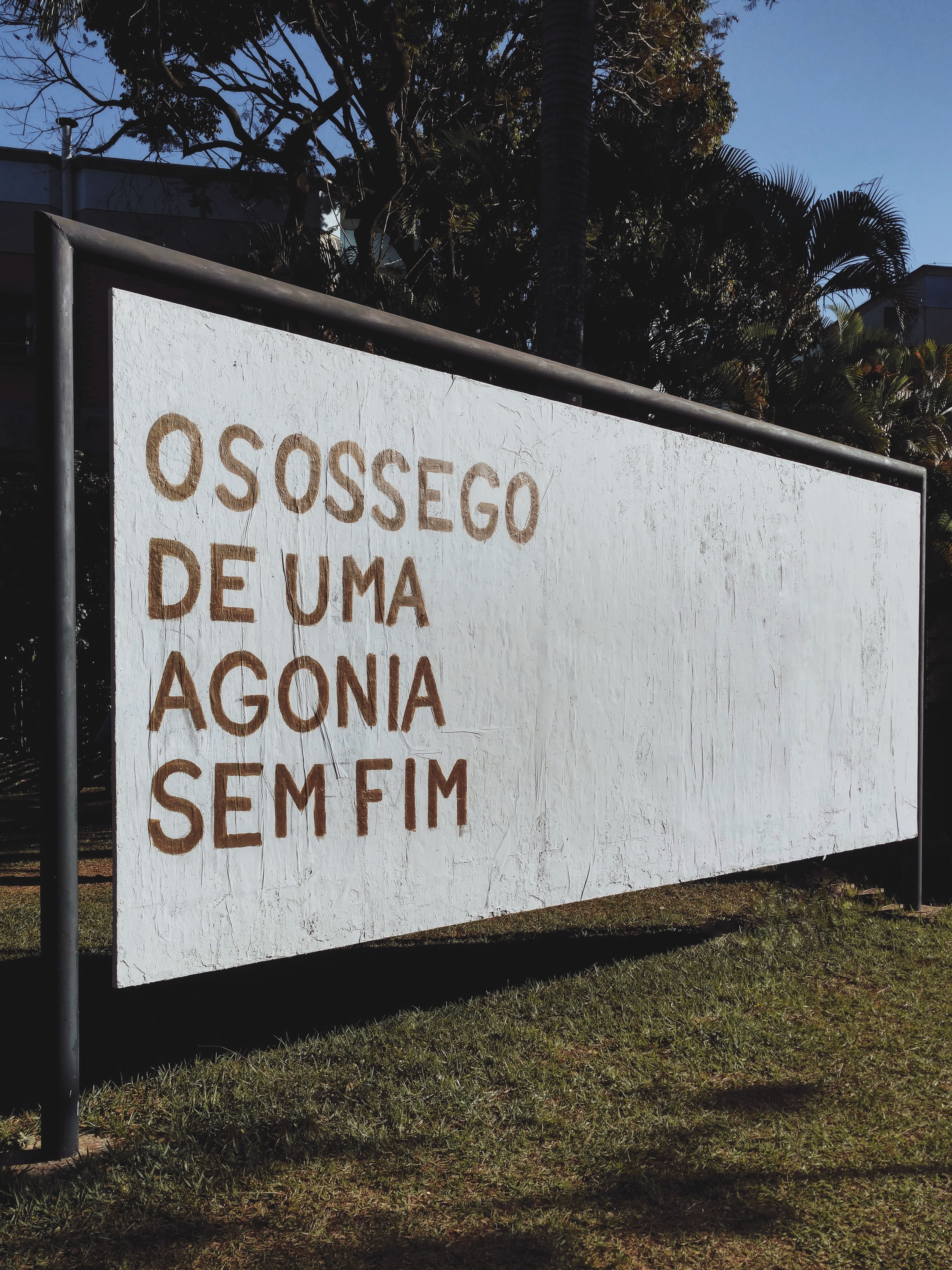 Sign with poetic text 'O Sossego de Uma Agonia Sem Fim' in Belo Horizonte park.