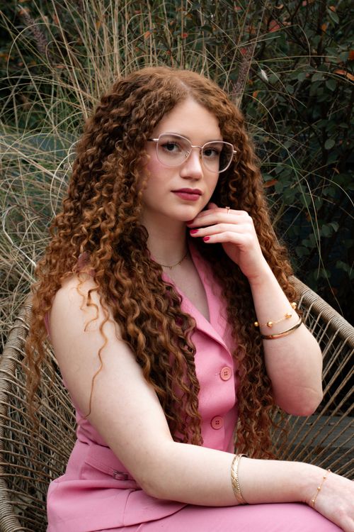 Free Stylish woman with curly hair and glasses seated outdoors in São Paulo, Brazil. Stock Photo
