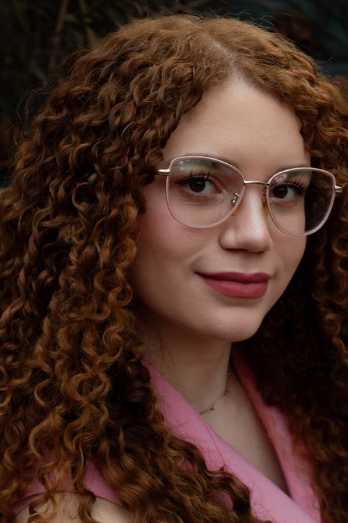 Portrait of a Woman with Curly Hair and Glasses · Free Stock Photo