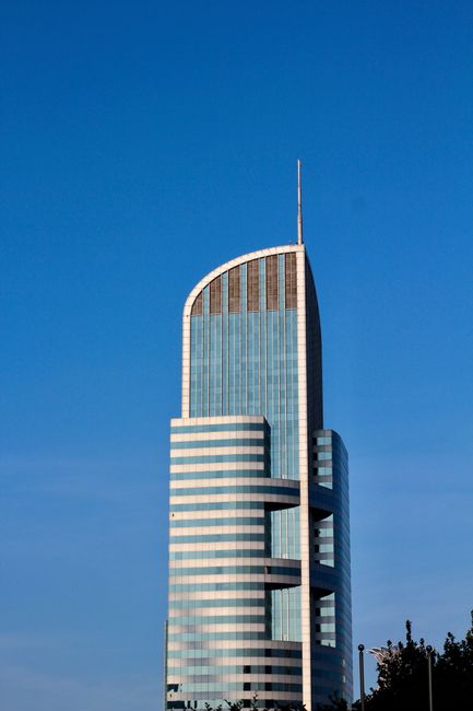 Fotomural Un rascacielos moderno con una arquitectura única frente a un cielo azul claro.