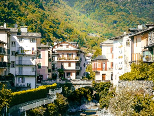Free Scenic view of a picturesque alpine village with colorful houses nestled amidst lush green mountains. Stock Photo