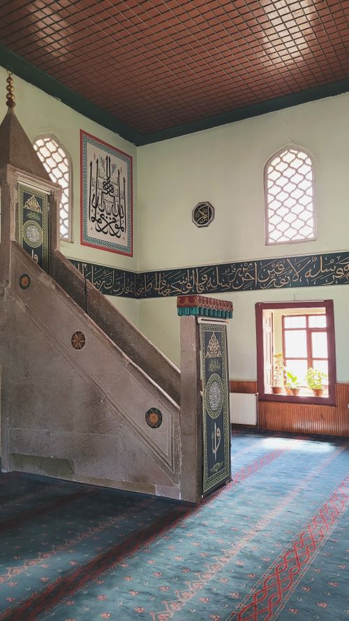Free Interior view of a mosque featuring a traditional minbar, intricate calligraphy, and decorative windows. Stock Photo