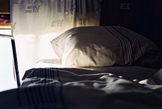 Soft morning light illuminates a cozy train cabin bed in Lviv, Ukraine.