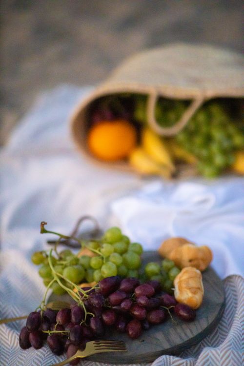 Free Fresh fruits and pastries elegantly spread out on a beach picnic at sunset. Stock Photo