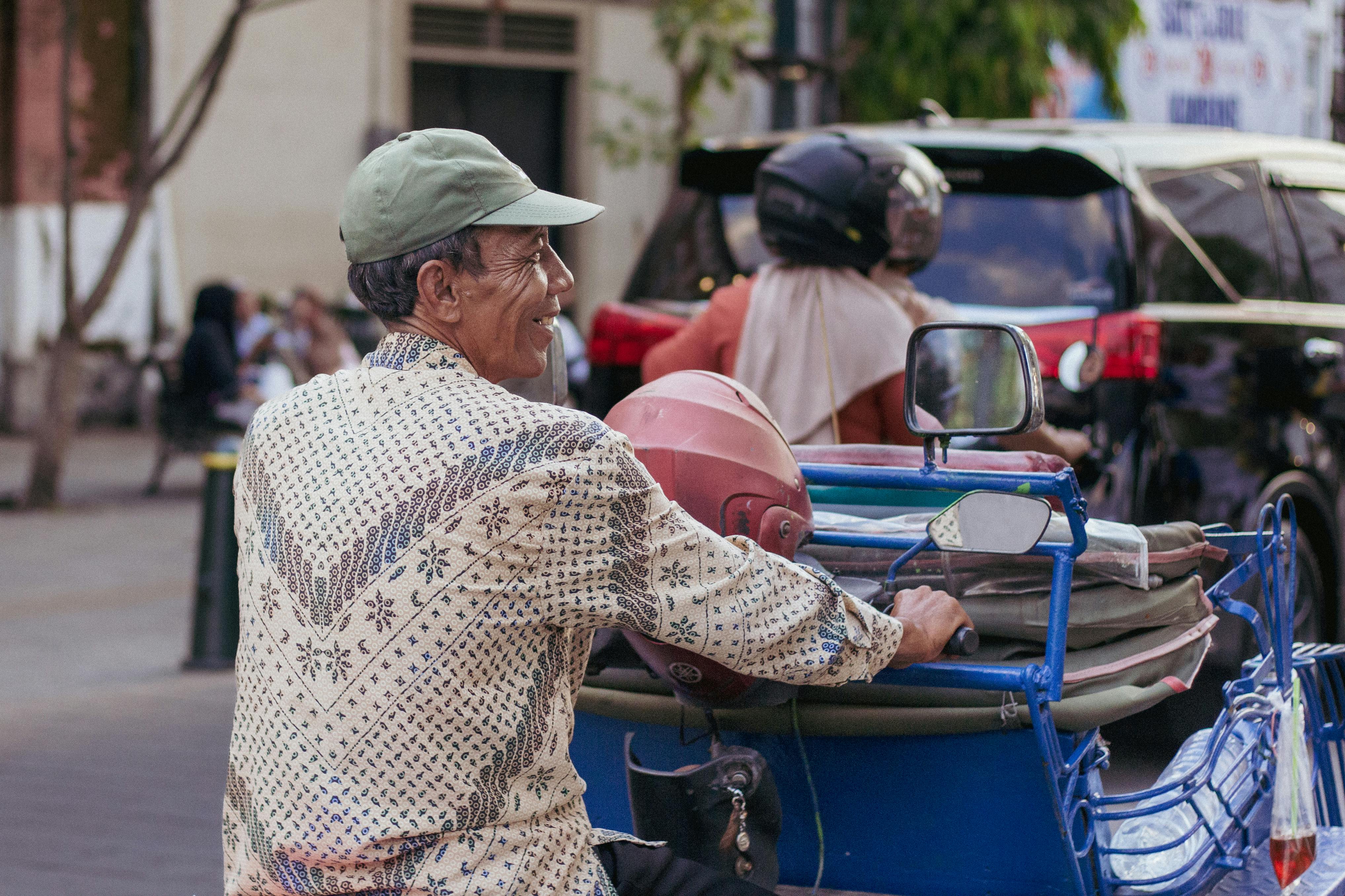 Candid shot of a senior man driving a pedicab on a busy street.