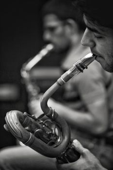 Black and white photo of musicians playing saxophones, capturing emotion and intensity.