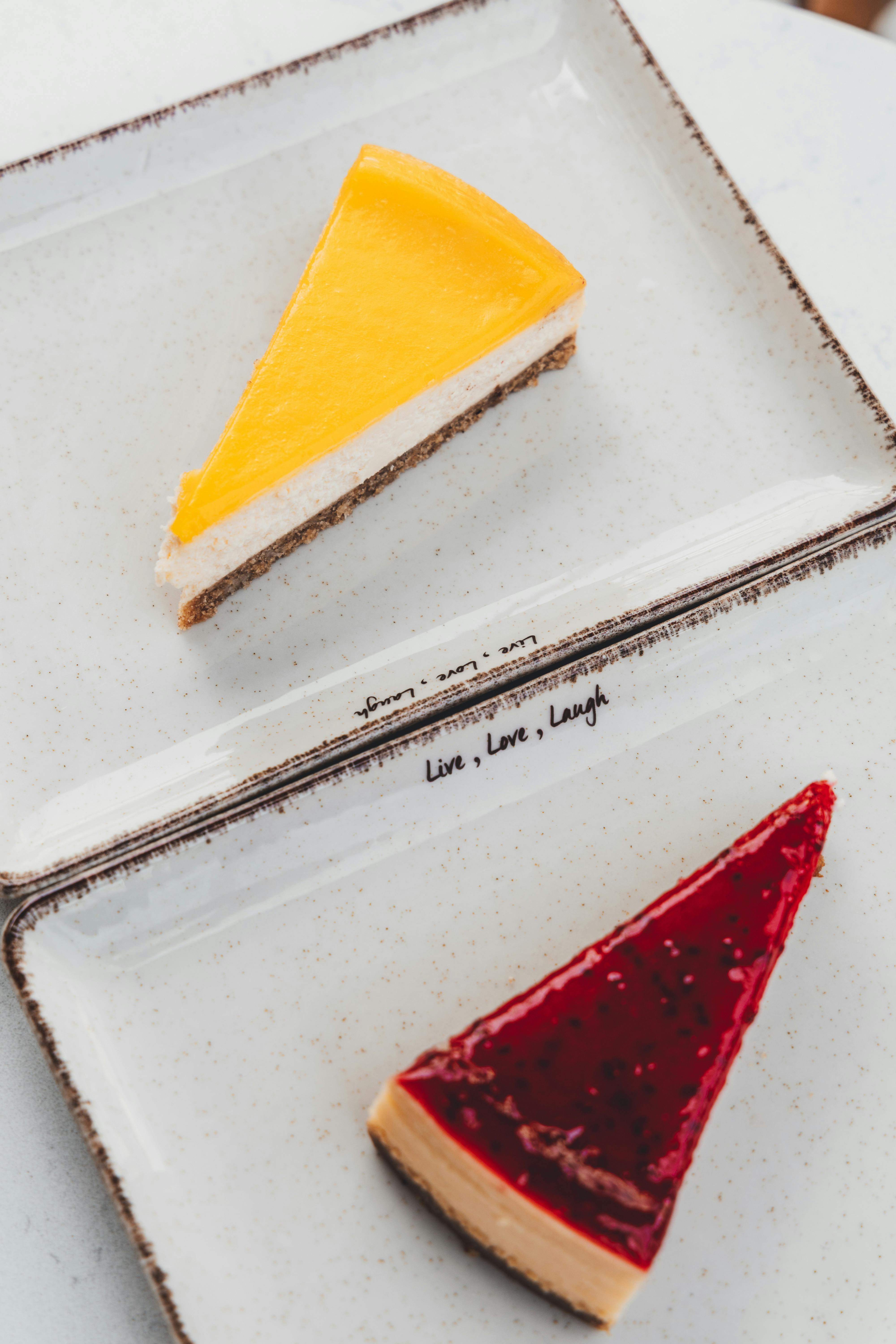 Two slices of cheesecake with lemon and berry toppings on stylish plates. Perfect for dessert inspiration.