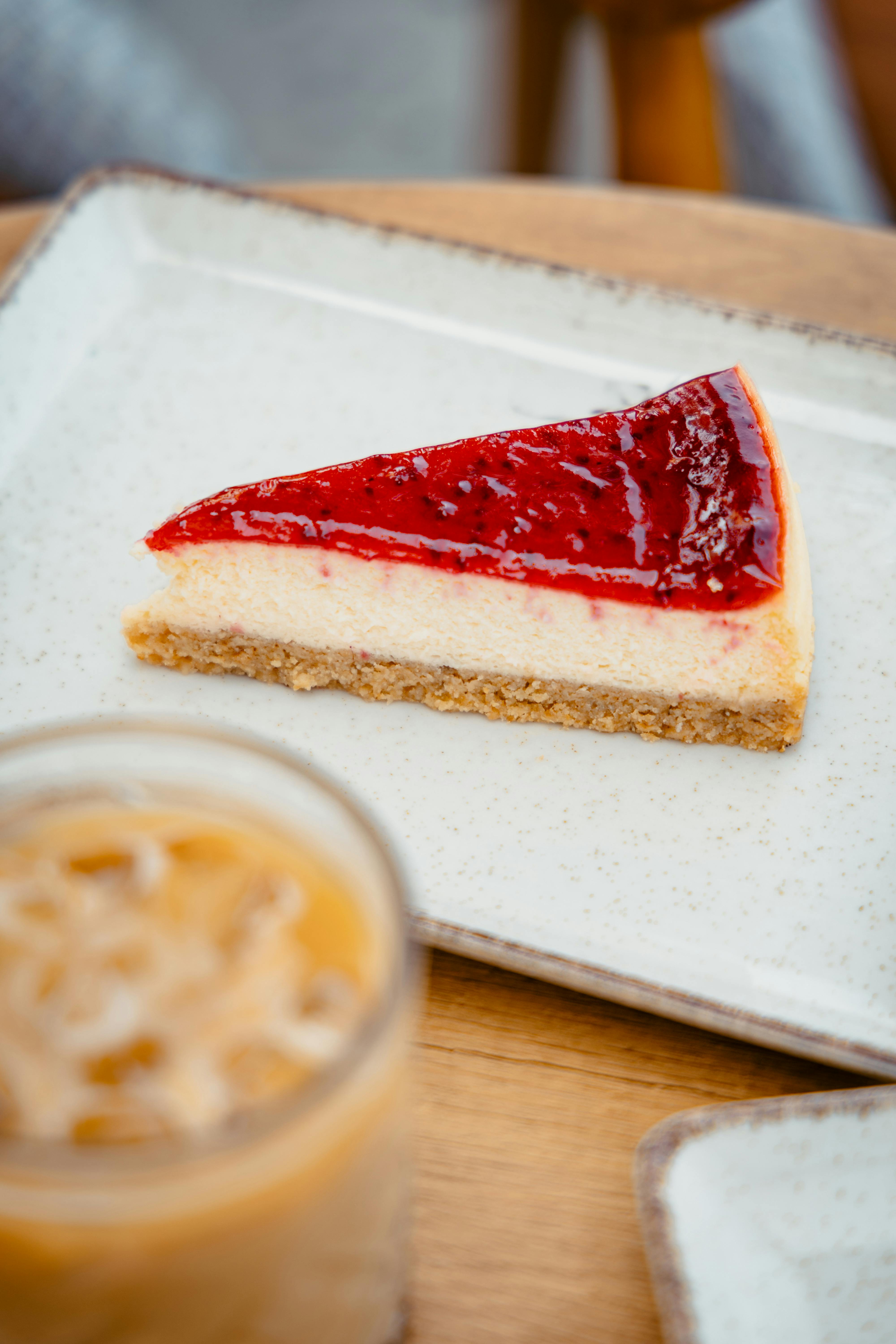 A tempting slice of strawberry cheesecake paired with an iced latte, perfect for dessert lovers.