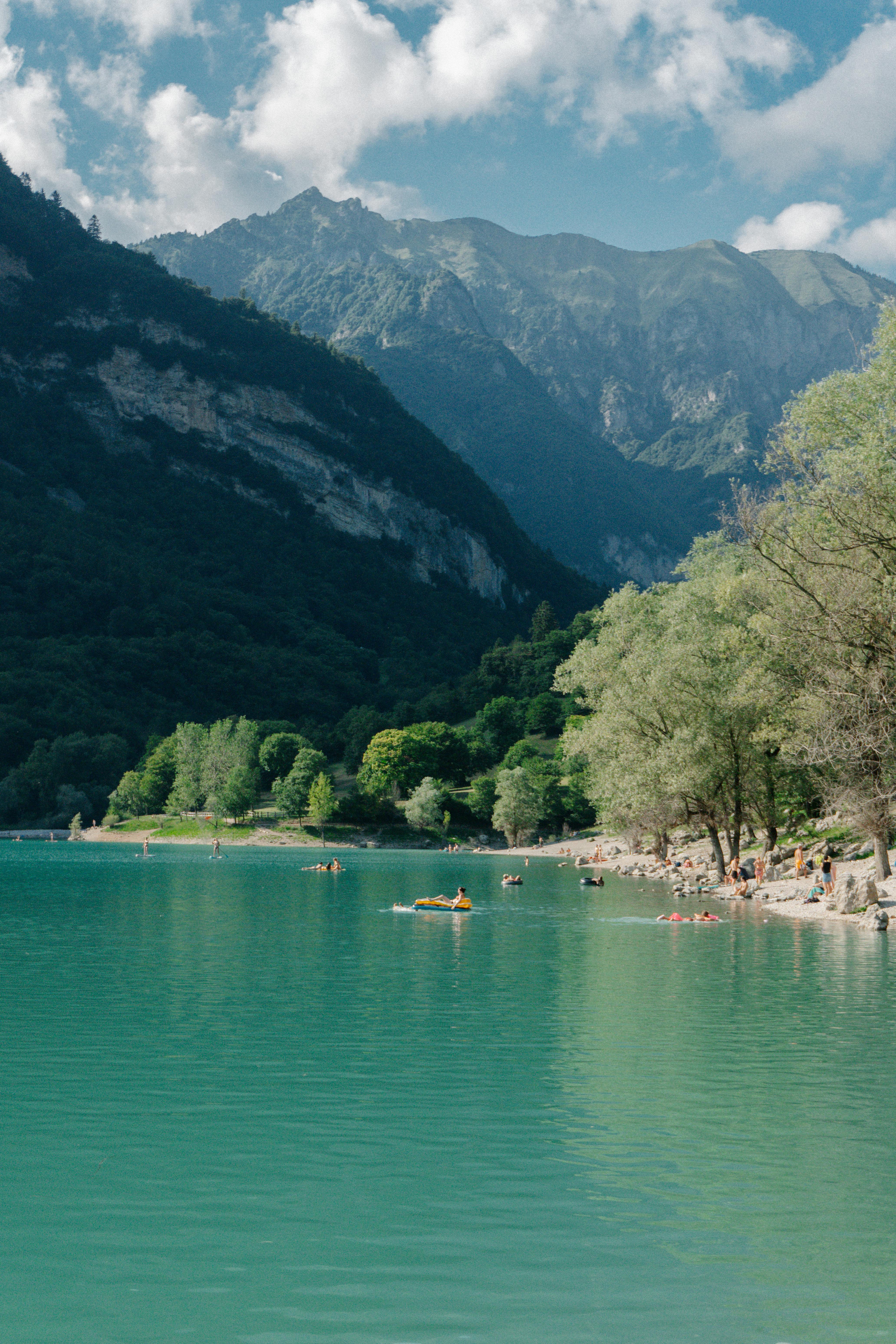 Majestic view of the lake and mountains in Trentino-South Tyrol, Italy, with people enjoying a summer day outdoors.