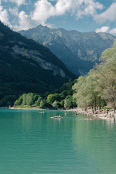 Majestic view of the lake and mountains in Trentino-South Tyrol, Italy, with people enjoying a summer day outdoors.