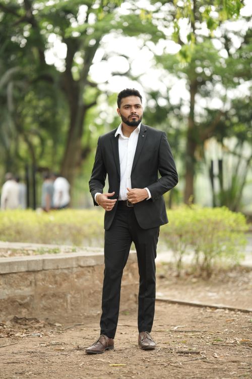 Free A businessman in a suit poses outdoors, exuding confidence and style in a park setting. Stock Photo