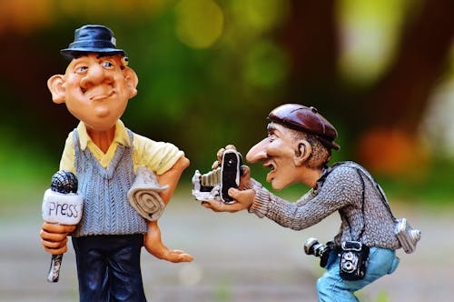 Free Man Taking Photo Of Man Standing Beside Him Holding Press Microphone Statue Stock Photo