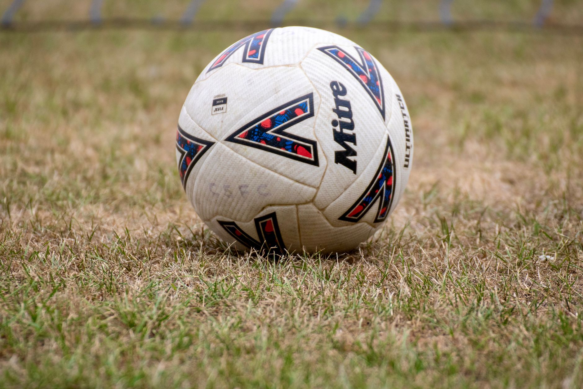 Close-up of a soccer ball on dry grass in Tipton, England. Perfect for sports and recreation themes.