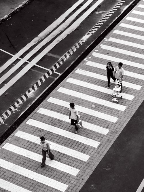 Free Aerial view of people crossing a city street in black and white, showcasing urban life. Stock Photo