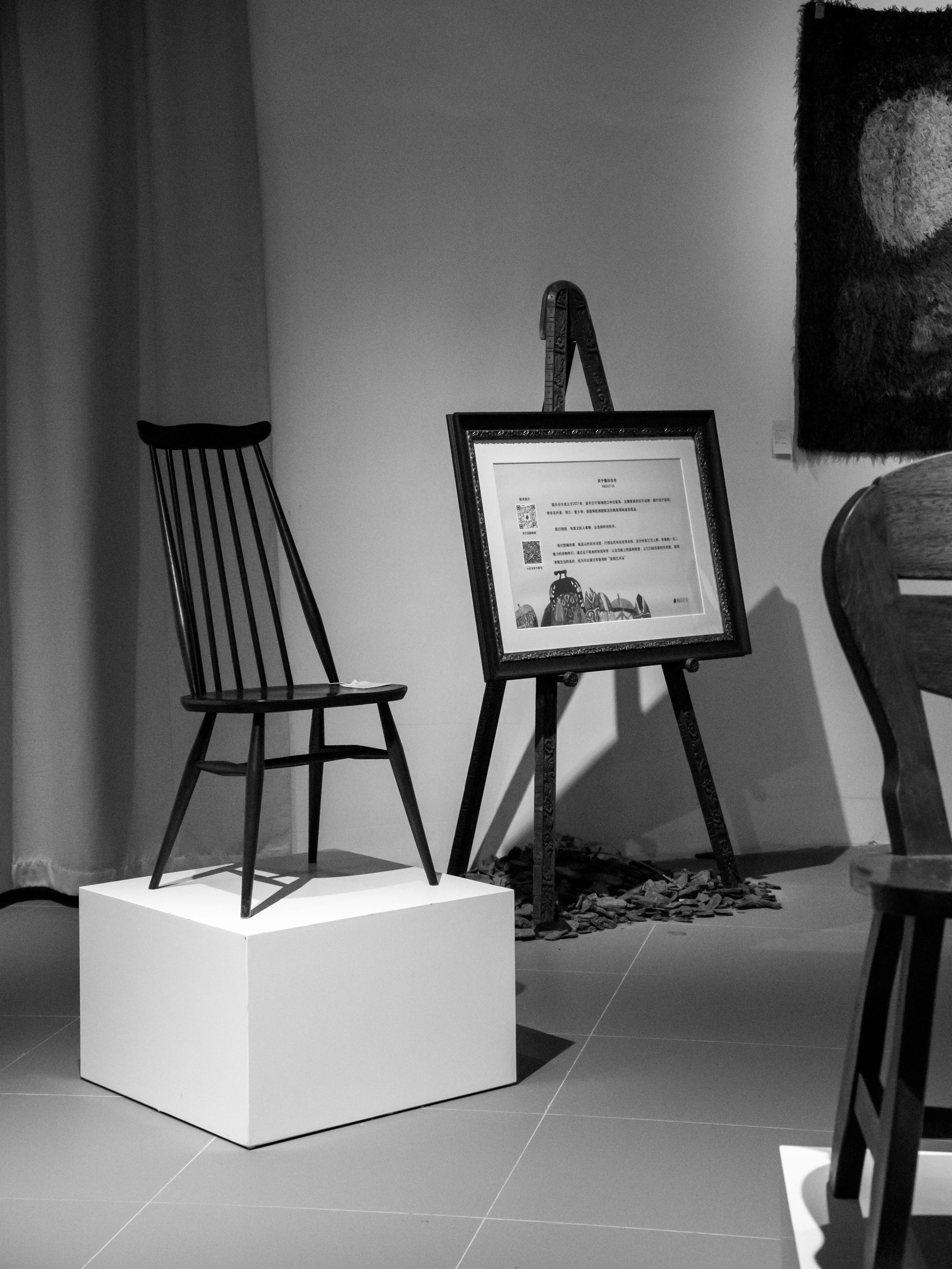 A chair and framed artwork on display in an art gallery, the line between furniture and sculpture deliberately blurred.